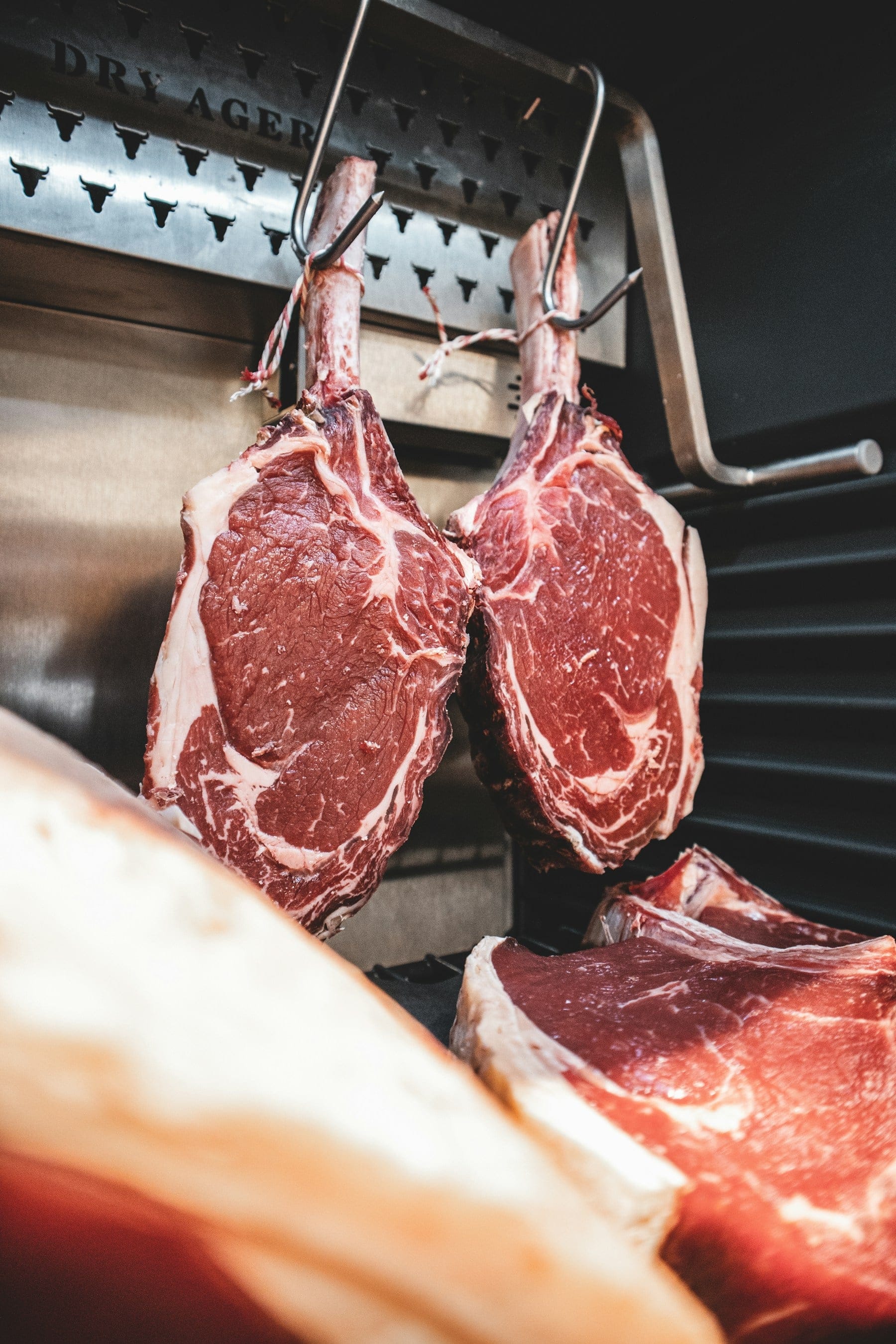 Bone-in beef rib sections hanging in a cold room