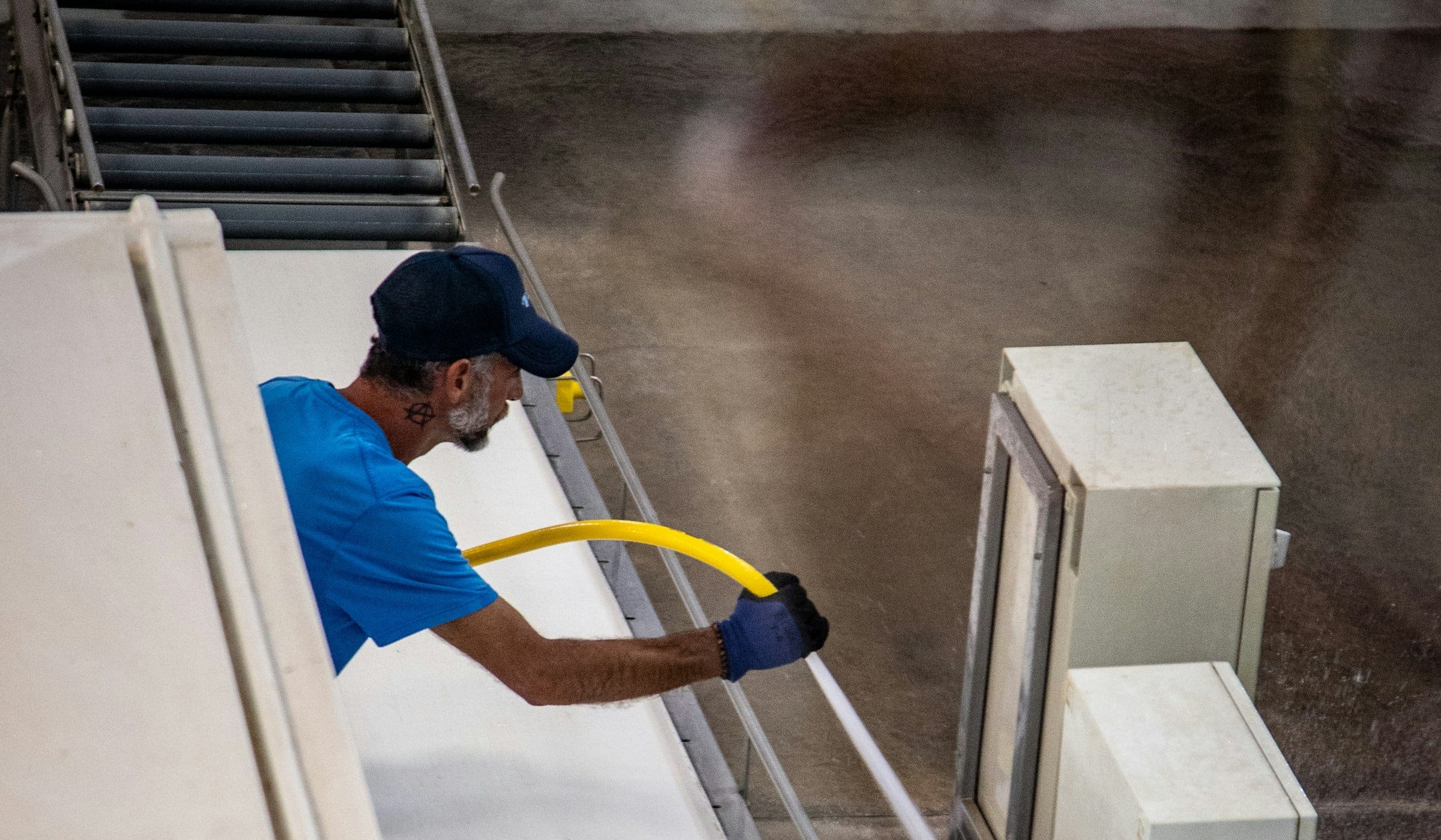 Worker hosing down a production line